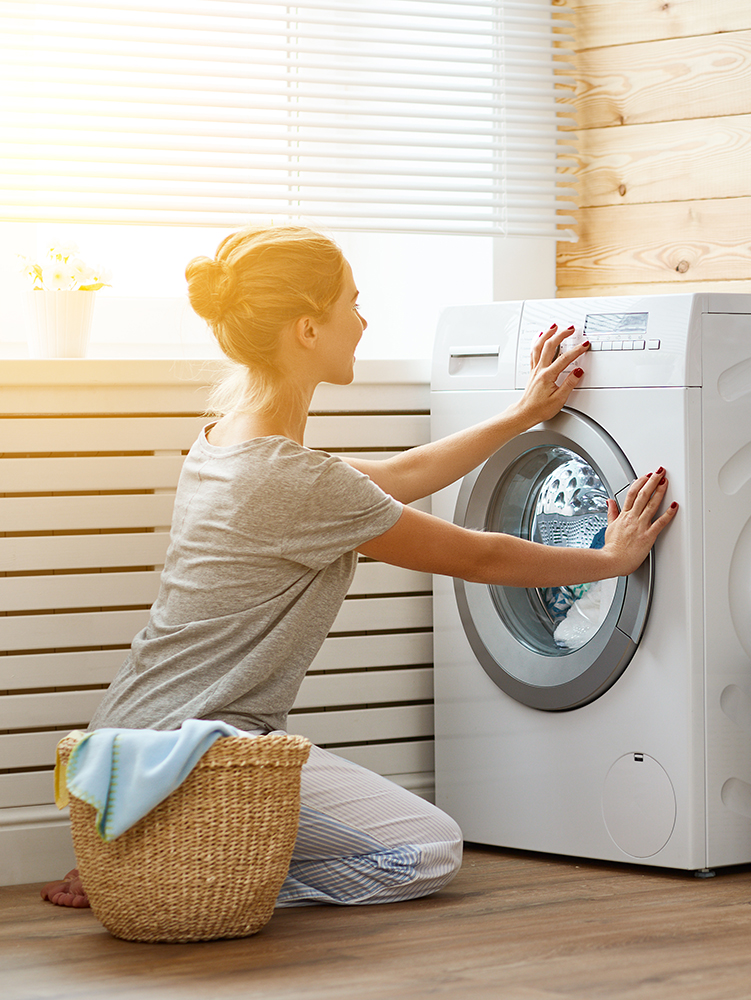 Happy housewife woman in laundry room with washing machine Happy housewife woman in laundry room with washing machine